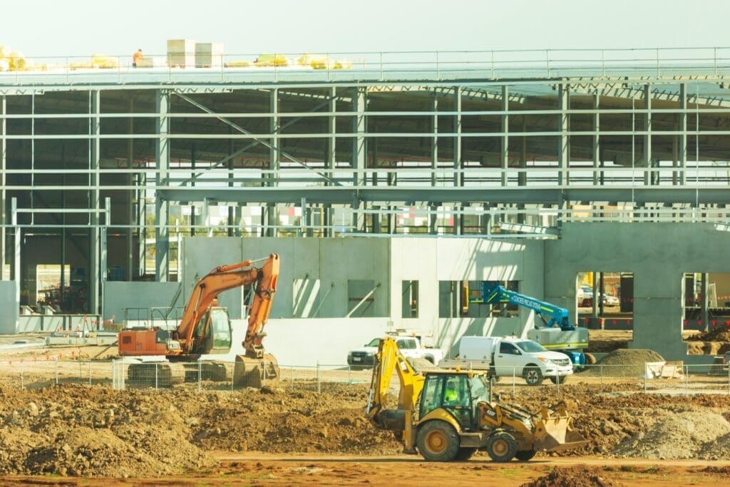 yellow and black excavator near white building during daytime